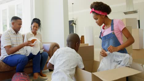 vista frontal de una joven familia negra desempaquetando cajas de cartón en un hogar cómodo 4k