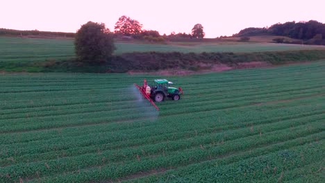 cerrar vista aérea de tractor agrícola rociando al atardecer