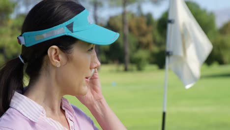 jugadora de golf hablando por teléfono móvil mientras juega al golf