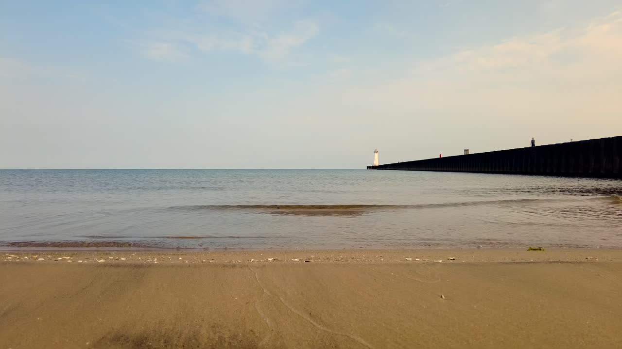 온타리오 호수 기슭 땅 끝에 있는 소더스 포인트 뉴욕 휴양지에 있는 등대에서 멀리 있는 등대를 향해 달리는 조깅하는 사람