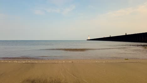 Jogger-running-to-a-light-house-in-the-distance-of-the-light-houses-at-Sodus-point-New-York-vacation-spot-at-the-tip-of-land-on-the-banks-of-Lake-Ontario