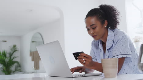 Mujer-En-Pijama-En-La-Cocina-Haciendo-Compras-Con-Tarjeta-De-Crédito-En-Línea-En-Una-Computadora-Portátil