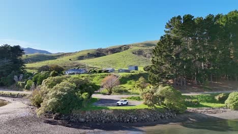 aerial footage captures akaroa's serene lakeside with lush greenery, rolling hills, and clear skies, highlighting natural beauty and tranquility