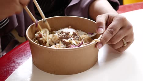 woman eating delicious beef bowl with chopsticks