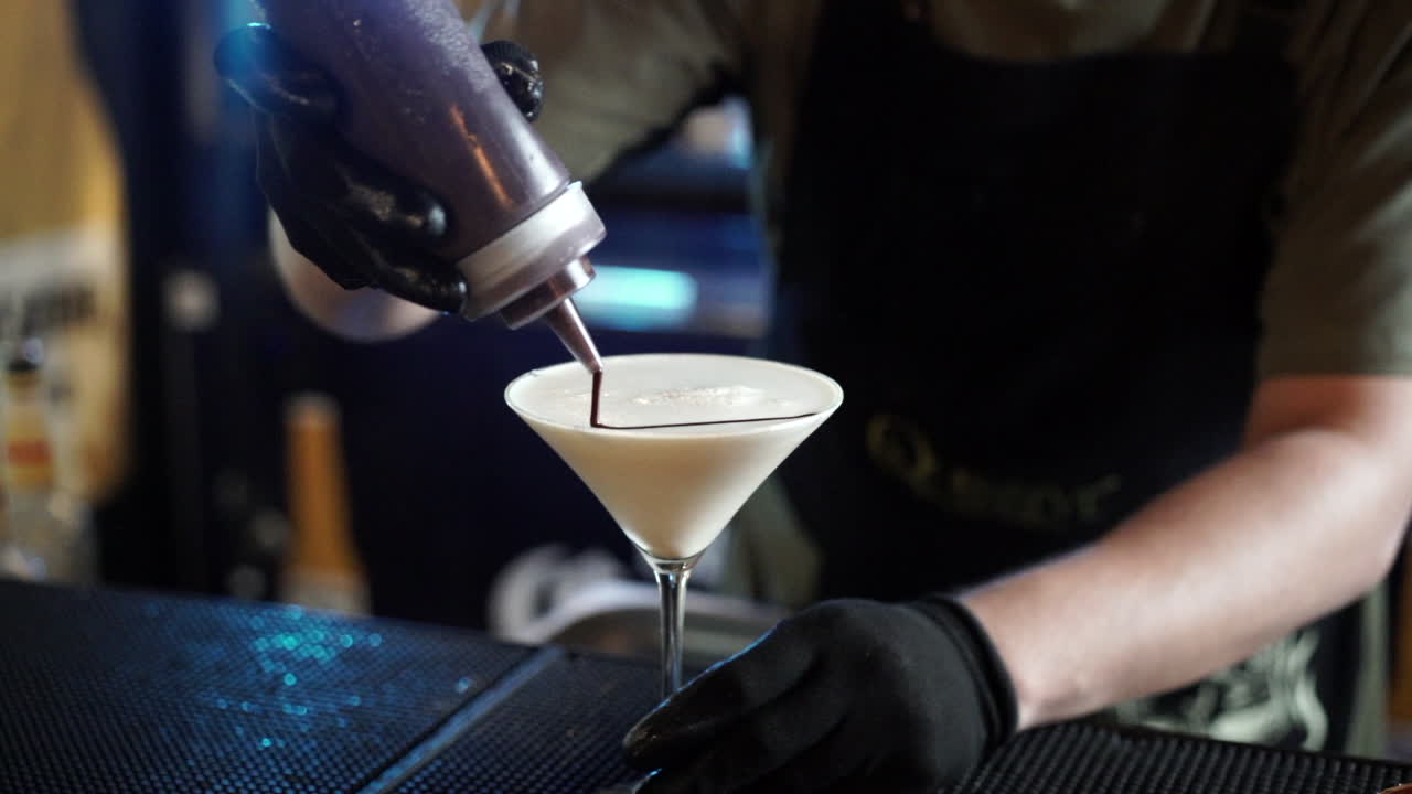 Barman che decora un cocktail con cioccolato al rallentatore.