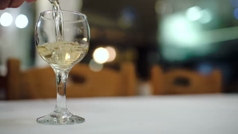 pouring white wine into glass in restaurant