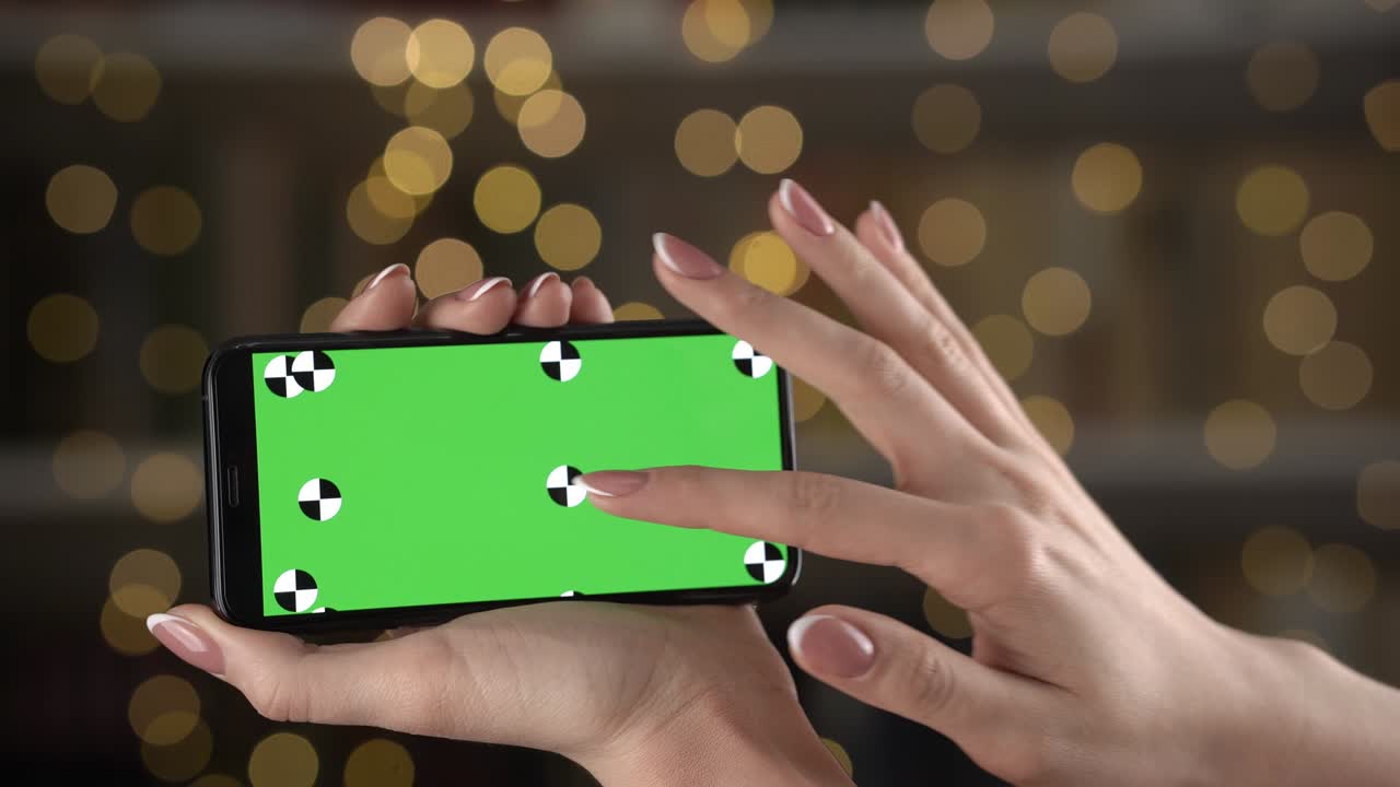 mujer sostiene un teléfono inteligente con marcadores de seguimiento en las manos y zooma el contenido con los dedos para encontrar algo