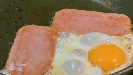 spam en cámara lenta y huevo chisporroteando en una sartén huevos soleados desayuno con colesterol alto