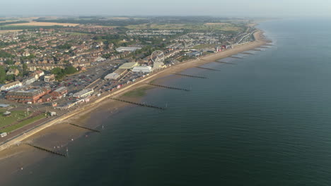 Hoch-Etablierte-Luftdrohne,-Die-über-Die-Küstenstadt-New-Hunstanton-Mit-Buhnen-Am-Sandstrand-Und-Riesenrad-Und-Vergnügungspark-Mit-Ruhiger-See-Mit-Kleinen-Wellen-Im-Norden-Von-Norfolk-Großbritannien-Fliegt