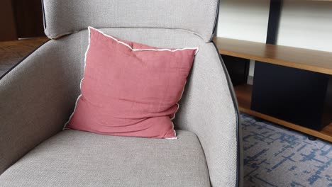 gray armchair with a reddish-pink pillow