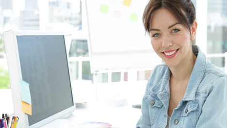 Beautiful-smiling-creative-designer-working-sitting-at-her-desk-