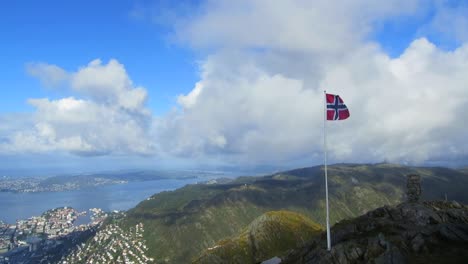 norwegian flag waving on top of mountain above city