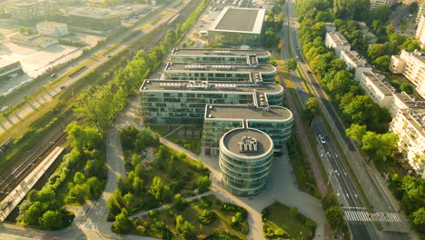 aerial view of modern building surrounded by green trees and cars on road in gdynia