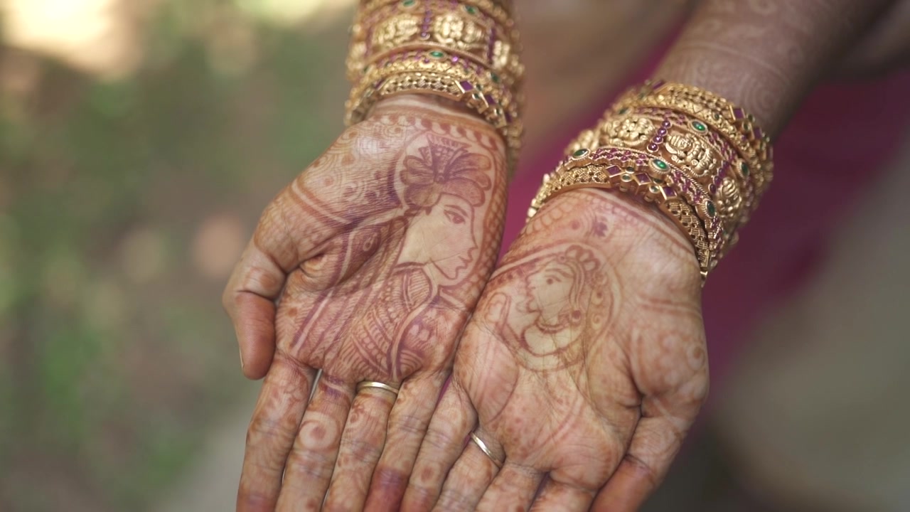 Primo piano della mano di una sposa indiana con Mehendi e gioielli