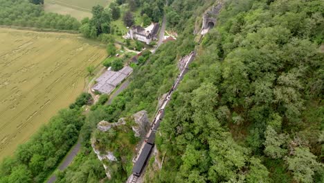 aerial view of a small steam train carrying tourists, in the middle of a cliff, in the martel region in summer, dordogne, france