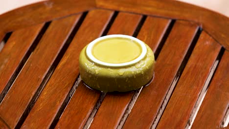 upside yellow ceramic ashtray on a wooden table outdoors with pouring rain in the garden