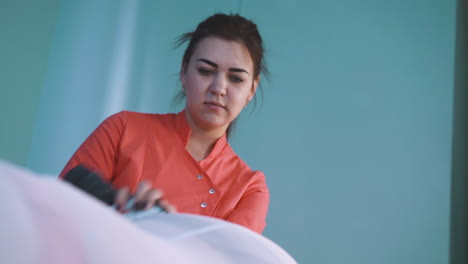 cosmetologist in uniform does roller massage of girl hip