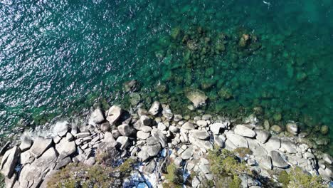 aerial view of clear blue lake tahoe water and beach rocks topdown