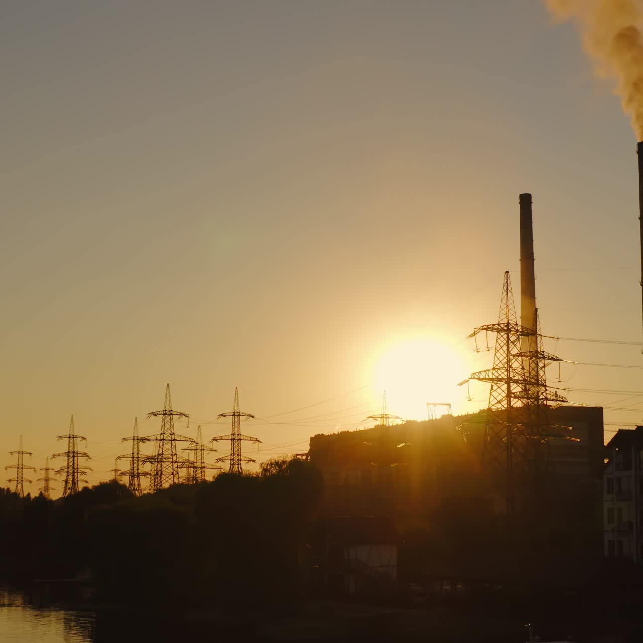 Silhouette of industry at sunset. Harmful smoke from pipe of manufacturing pollute the atmosphere in the evening.