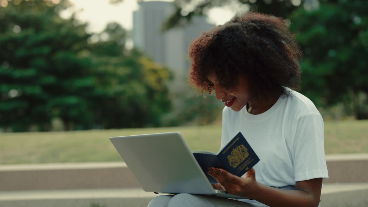 Woman checking passport on a laptop in the park