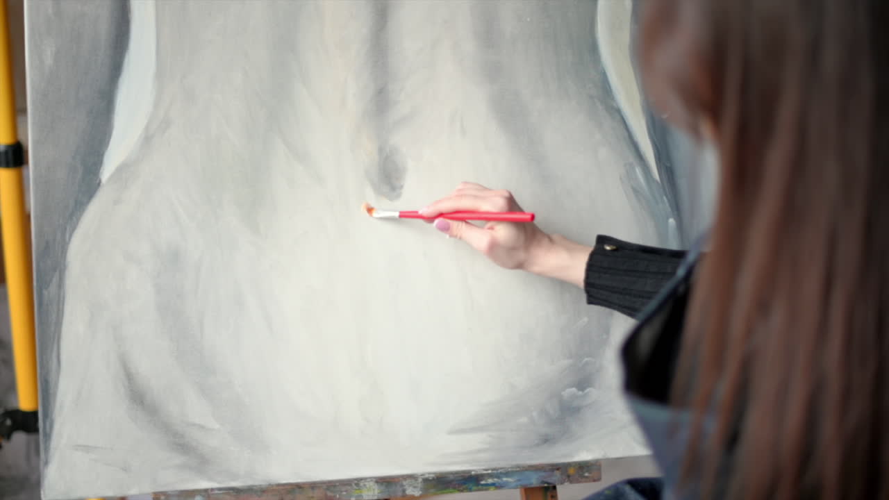 Woman painting a female body on a canvas at an art gallery workshop