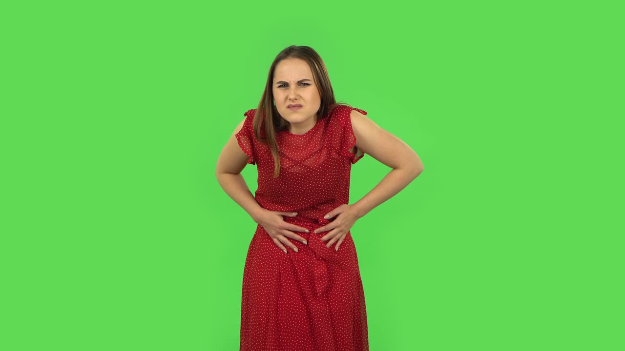 Tender girl in red dress is feeling very bad, her stomach hurting. Green screen