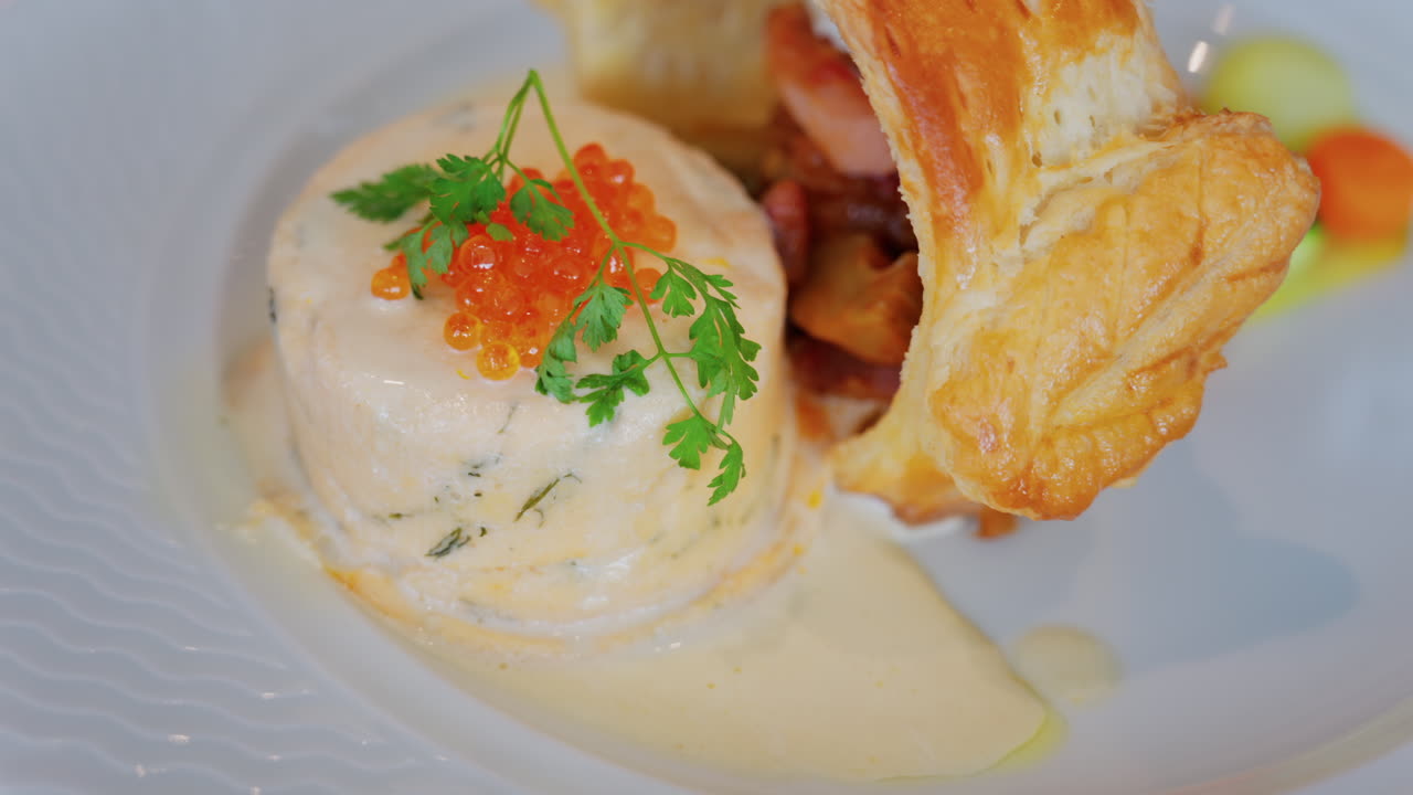 Close up of a fish mousse with salmon roe and puff pastry on a white plate at a restaurant