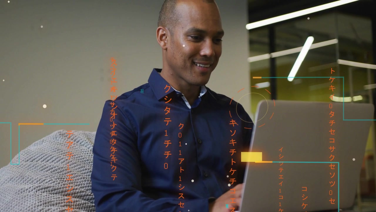 Mid-adult man typing on laptop in office, orange teal glyphs guiding business workflow, smiling
