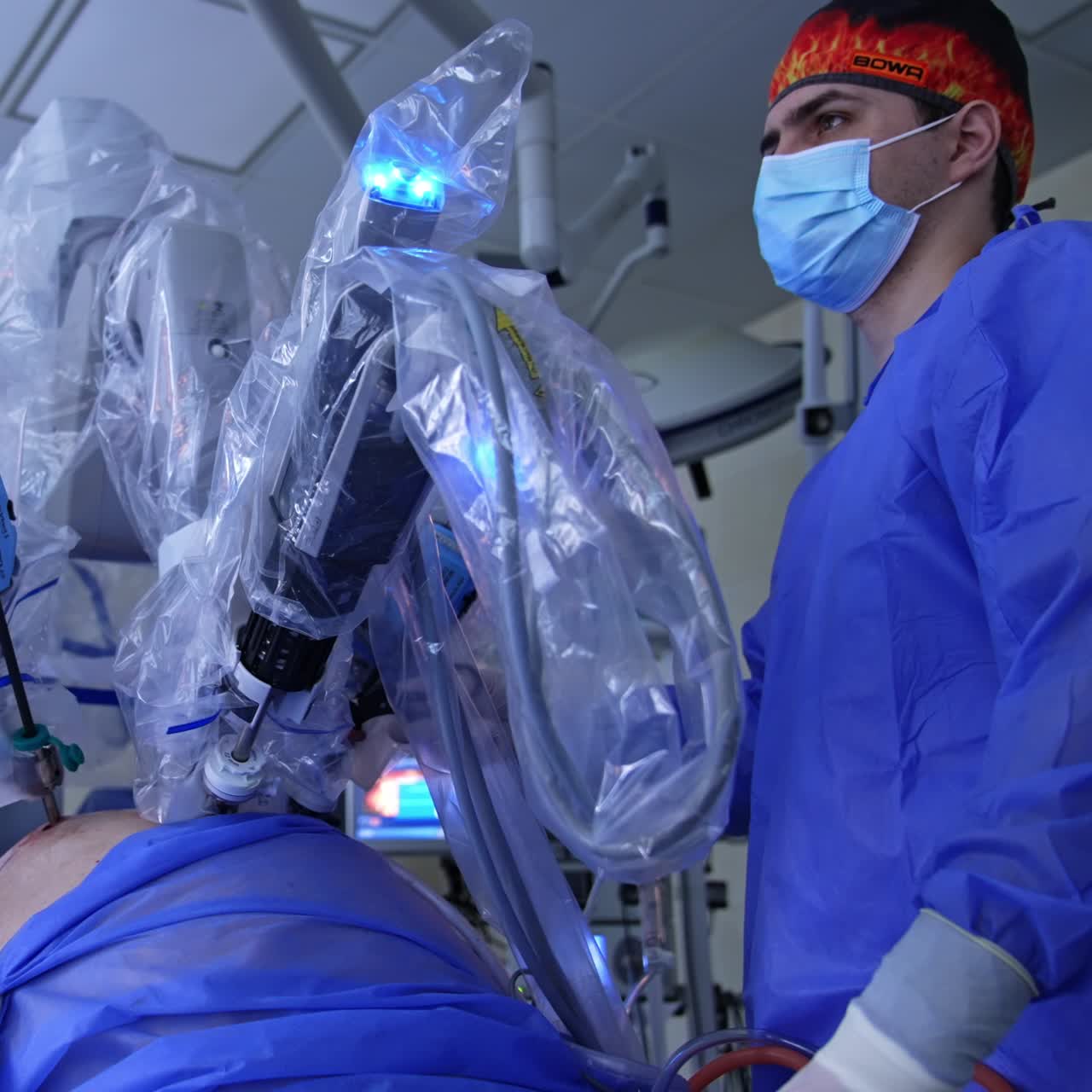 High-precise technological robot operating the patient. Male doctor stands beside looking at the screen and controlling the procedure. Low angle view