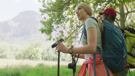 Happy-diverse-couple-hiking-with-backpacks-in-park,-slow-motion