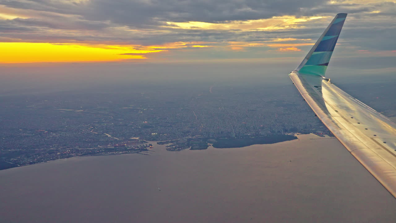 Pemandangan Udara Kota dan Laut Saat Matahari Terbenam dari Jendela Pesawat