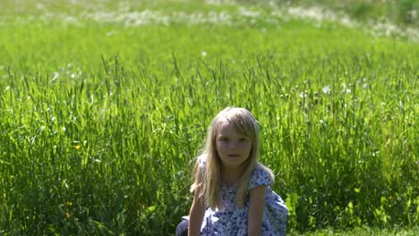 Long-shot-of-four-year-old-girl-staring-right-at-the-camera,-playing-outdoor-in-summer