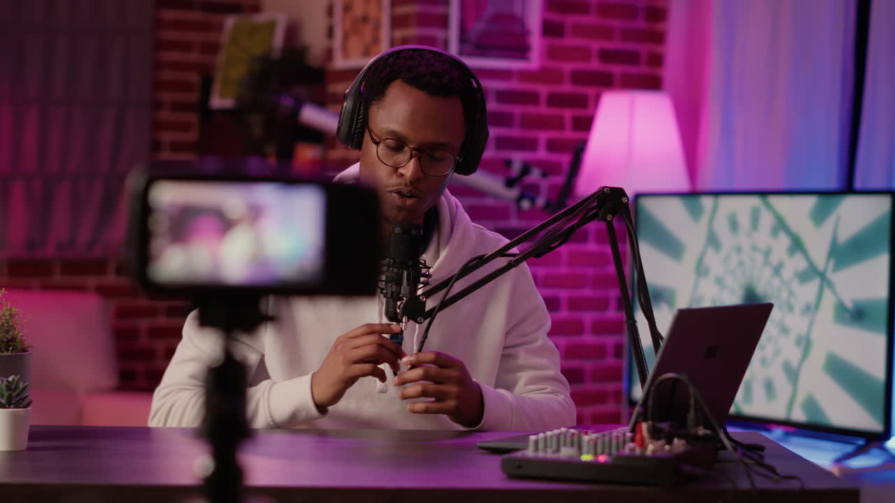 Online radio host answering internet call from listener while recording vlog using digital video camera