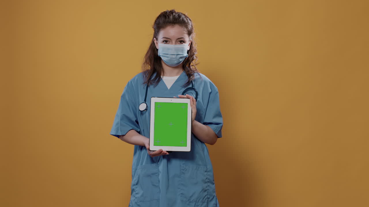 A medical professional with an ipad showing a green screen