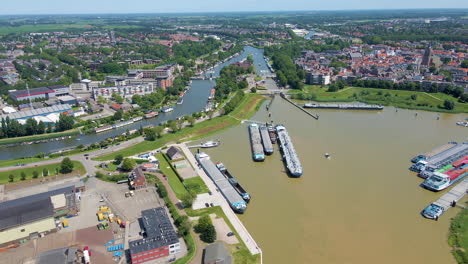 Antenne-Eines-Kleinen-Bootes,-Das-An-Großen-Angedockten-Frachtschiffen-Vorbeisegelt