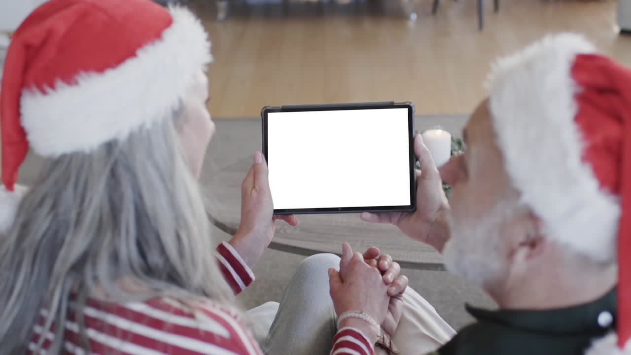 Happy caucasian senior couple having christmas tablet video call with copy space, slow motion