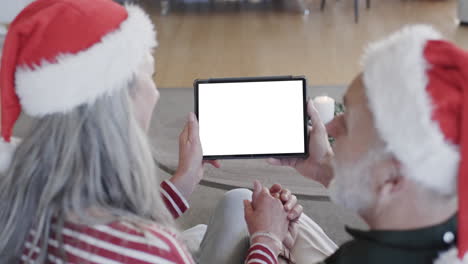 feliz pareja de adultos mayores caucásicos teniendo navidad tableta llamada de video con espacio de copia, cámara lenta