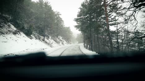 car drive forest road during snow fall windshield view in slow motion