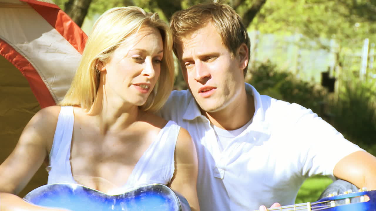 어머니 는 아버지 와 함께 노래 하는 동안 기타 를 연주 하고 있다