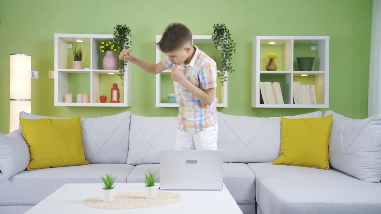Little boy trying to box at home. His older brother teases his younger brother.