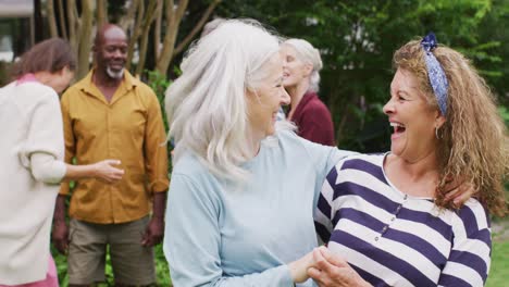 animation of happy diverse female senior friends embracing in garden