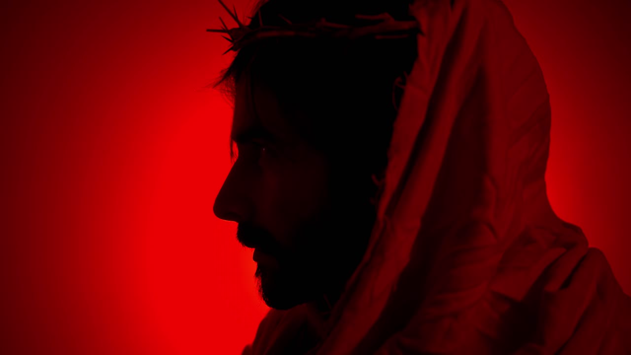Silhouette of Jesus Christ Wearing Crown of Thorns in Red Light for Christianity, Easter visual or bible scene.