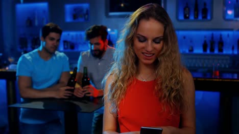 mujer elegante enviando mensajes de texto y dos hombres sentados en la mesa