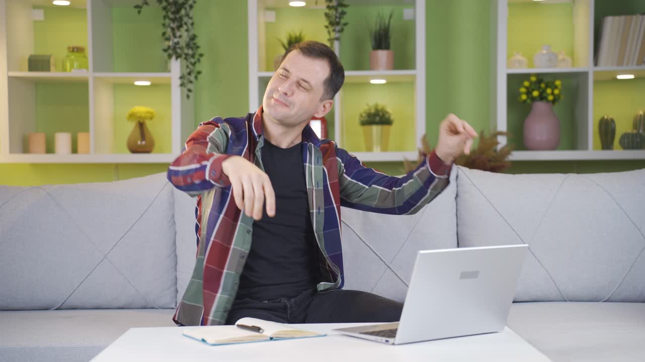 el hombre con la computadora portátil frente a él comienza a bailar mientras mira la pantalla.