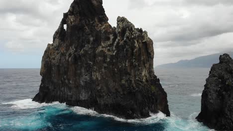 The-drone-maneuvers-near-the-striking-rock-formations-of-Ribeira-da-Janela,-showcasing-their-rugged-beauty-and-the-relentless-power-of-the-crashing-waves-below