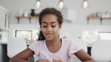 african american girl sitting at table, having video call, slow motion