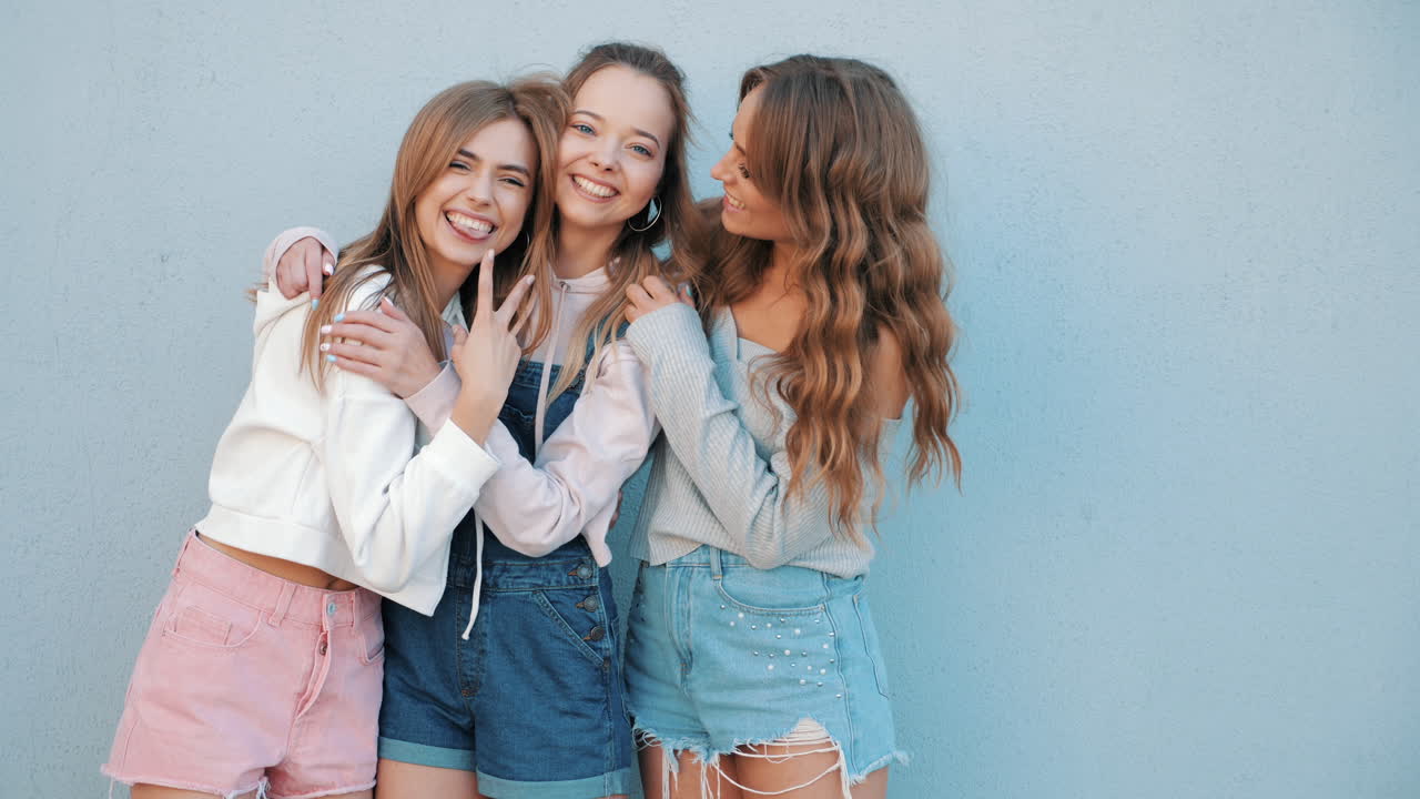 세 명의 행복한 젊은 여성들이 포옹하고 있습니다.