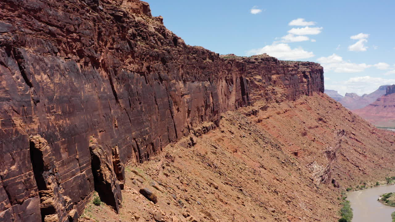 Majestuosos acantilados de arenisca roja se extienden por un paisaje accidentado con un río serpenteando por debajo en una tarde soleada