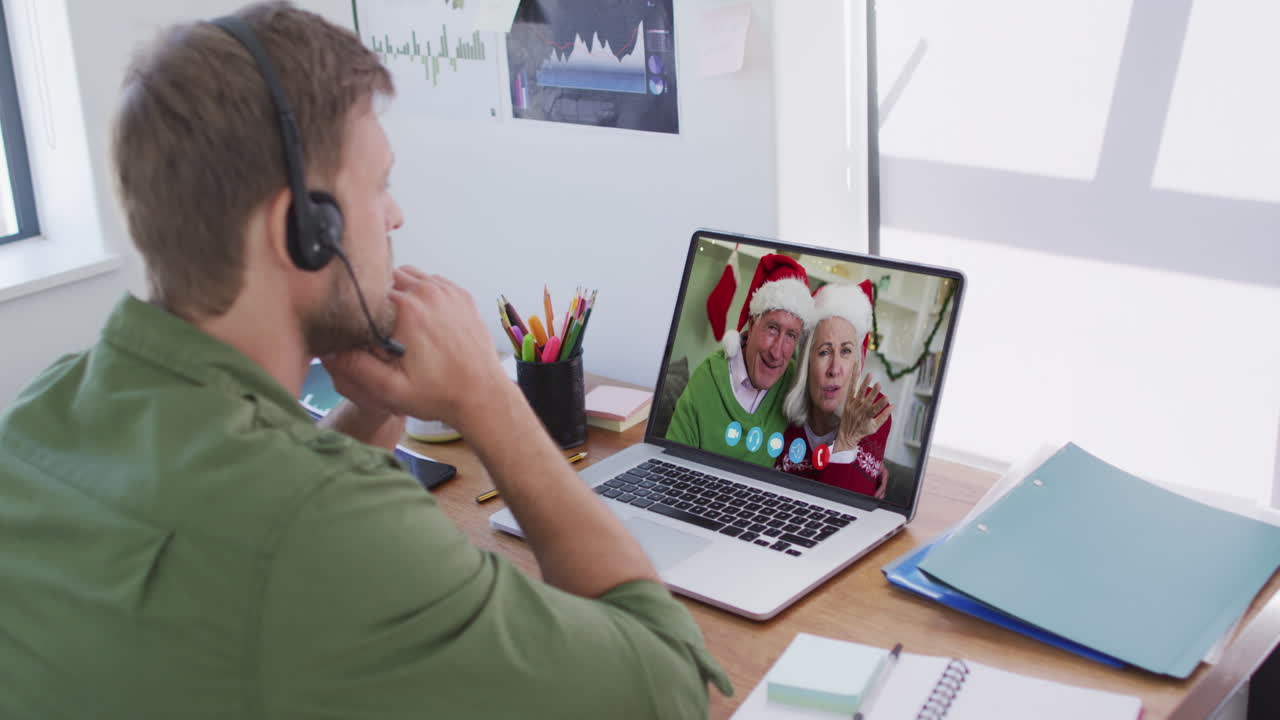 Kaukasisk mand med telefonheadset på videochat via bærbar computer derhjemme i julen.
