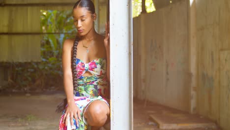 Grafitti-art-on-the-wall-in-the-background-while-a-young-woman-squats-on-a-beam-in-an-abandoned-warehouse